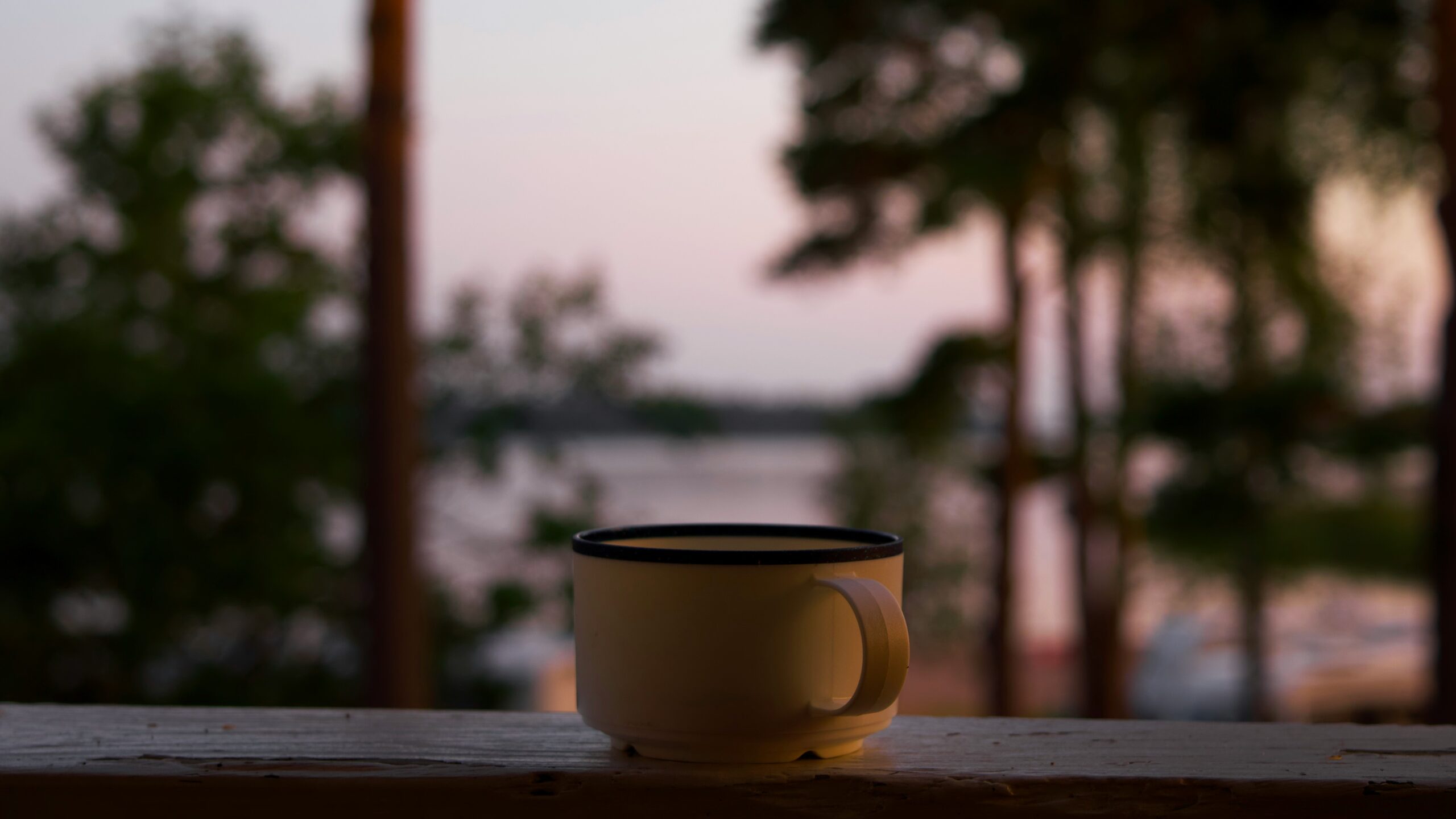 Smiling person holding a cup of tea during sunrise outside