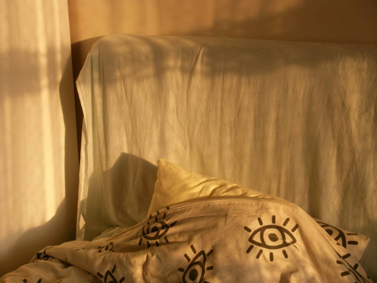 A bed with a patterned duvet and sunlight