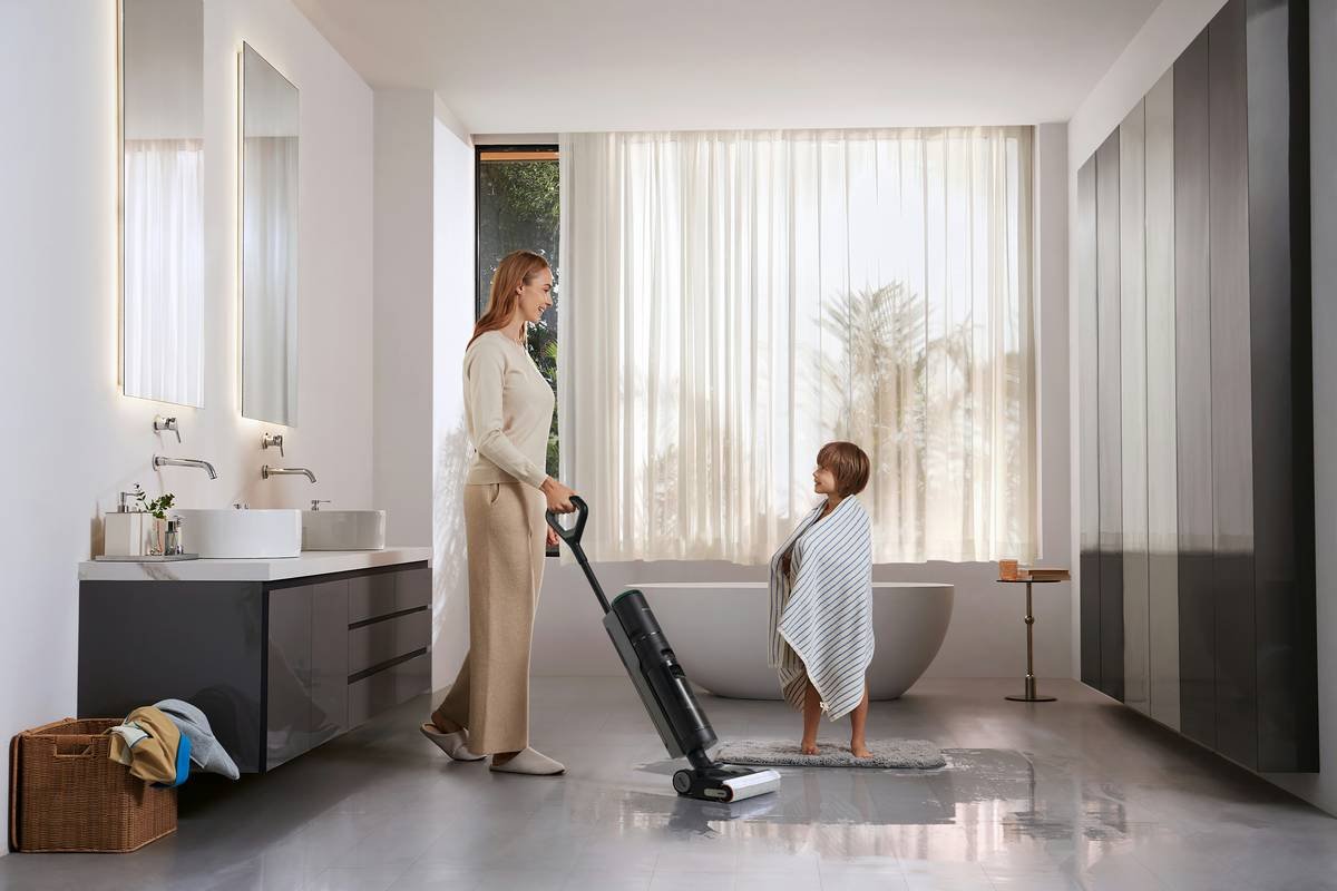 A mother uses a Dreame wet dry vacuum to clean bathroom tiles after her son’s bath, showcasing fast cleanup for everyday messes.